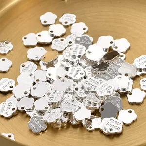 Nahaufnahme von blumenförmigen silbernen Metallanhängern mit Hand made Gravur für DIY