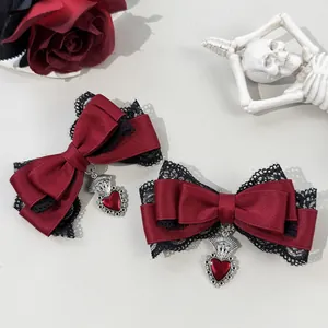 Close-up detail of gothic wine red bow hair clips with black lace and red heart pendants.
