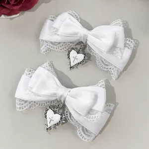 Close-up of white lace bow hair clip with silver heart cross pendant decoration.