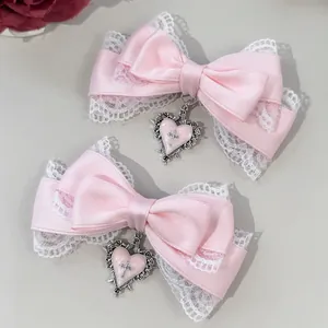 Detail view of pink bow hair clips with lace trim and heart cross pendants