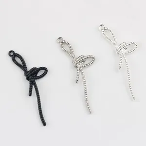 Gros plan de trois pendentifs nœuds en alliage noir et argent pour la création de bijoux DIY.
