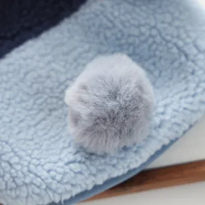 Close-up detail of warm sherpa fleece pet hoodie with soft decorative gray pom-pom.