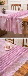 Detailed view of pink floral lace tablecloth with wavy edges on wooden table