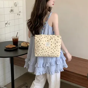 Dettaglio della borsa tote in velluto a coste crema con motivi a cuore e perline.