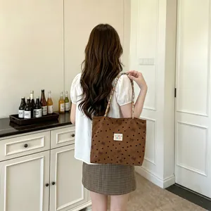 Vista dettagliata lifestyle della borsa a tracolla in velluto marrone con piccoli fiocchi