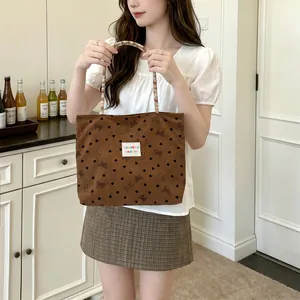 Modella con borsa tote in velluto a coste marrone con motivi a cuore e fiocco in cucina