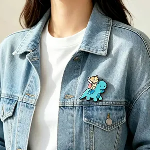 Close-up detail of a cute cartoon dinosaur and mouse metal enamel pin on a denim jacket
