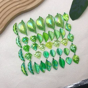Close-up of iridescent green artificial leaf charms in various botanical shapes for DIY.
