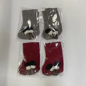Close-up of four Christmas stockings in grey and red, individually packaged in plastic bags.