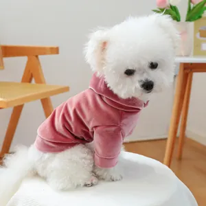 Close-up of white dog wearing a soft dusty pink velvet pet hoodie in cozy home setting