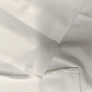Detailed close-up of stitching and smooth white fabric on an elegant summer dress.