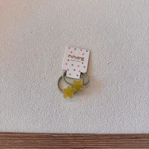Détail d'un chouchou étoile jaune à paillettes sur une carte d'emballage blanche.