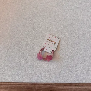 Détail d'un élastique à cheveux en forme d'étoile rose pailletée pour enfants sur carte