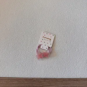 Gros plan d'élastiques à cheveux roses en forme d'étoile pour bébés sur une carte décorative