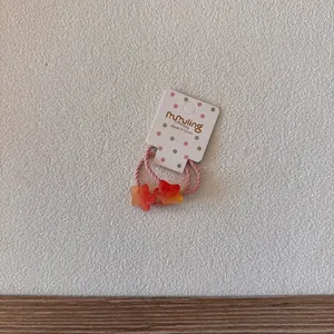 Vue détaillée d'un élastique rose avec des breloques en forme d'étoile orange