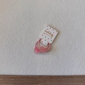 Vue détaillée d'élastiques à cheveux roses en forme de cœur sur une carte blanche.