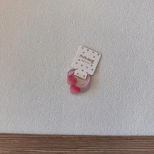 Détail d'un élastique à cheveux en forme de cœur rose givré sur sa carte support.