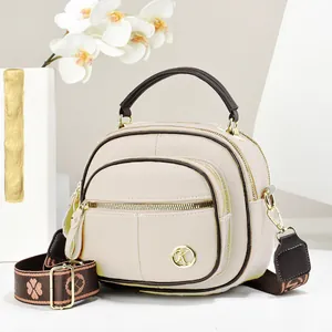Elegant beige round handbag with brown accents and a decorative wide floral strap.