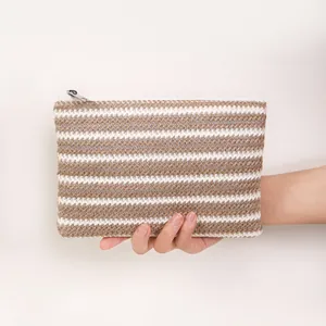 Minimalist brown and white striped woven makeup bag held in hand for travel use