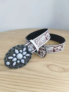 Primer plano de un cinturón retro con hebilla de mármol blanco y estampados western