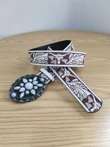 Detalle de cinturón vintage para mujer con hebilla de piedra blanca y estampado.