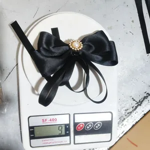 Detailed view of an elegant black ribbon bow brooch with pearl weighing 9 grams.