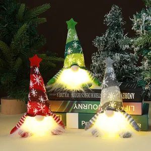 Close-up of three glowing LED knitted Christmas gnomes on book stack decor
