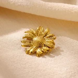 Gros plan détaillé d'une broche tournesol en acier inoxydable doré sur tissu texturé