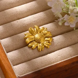 Détail d'une broche tournesol dorée en acier inoxydable sur un plateau à bijoux en velours beige