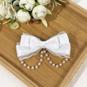 Detailed view of cream Lolita bow hair clip with delicate lace and pearl tassels