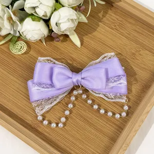 Detailed view of lavender satin bow hair clip with lace trim and pearl tassels