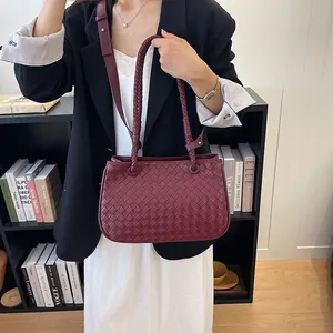 Close-up view of a burgundy woven leather shoulder bag styled with a professional chic outfit