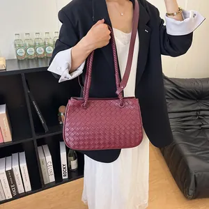 Detailed view of a premium burgundy woven shoulder bag featuring braided handles on a model