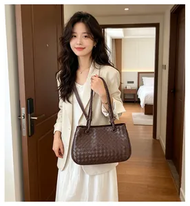 Stylish brown woven shoulder bag carried by a model in a modern home interior