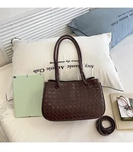Detailed view of dark brown woven tote bag resting on a white pillow in lifestyle setting