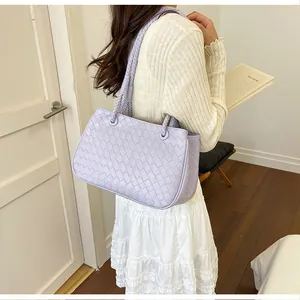 Stylish lavender woven handbag worn over the shoulder by a model in a casual setting