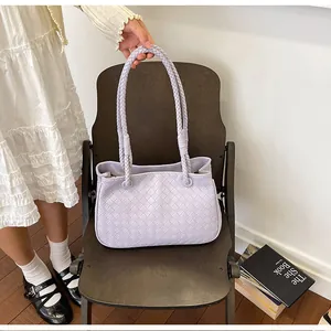 Detailed view of a stylish light purple woven shoulder bag on a dark wooden chair