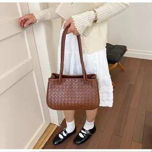 Fashionable brown woven handbag carried by a person in a casual lifestyle setting