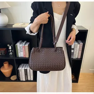 Stylish brown woven leather shoulder bag carried by a model in a modern interior