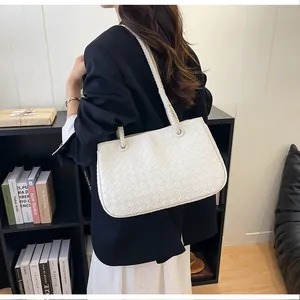 Detailed shot of a stylish white woven tote bag worn over the shoulder in a lifestyle setting