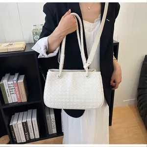 Close-up of white woven leather handbag with braided shoulder straps.