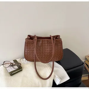 Detailed view of the brown woven leather texture on a stylish women's tote bag.