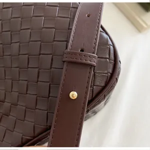 Close-up of premium dark brown woven leather bucket bag with adjustable strap detail.