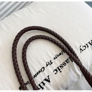 Close-up of a brown braided faux leather shoulder strap detail for a stylish handbag