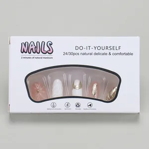 Detail of press-on nails kit with pink and white gold-accented tips in white packaging.