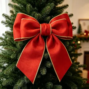 Large red velvet Christmas bow with gold wired edges on a green tree