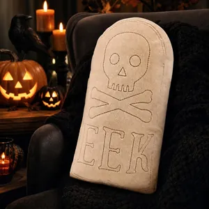 Detailed view of the embroidered skull and EEK text on the plush tombstone pillow.