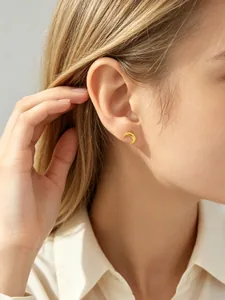 Close-up van een delicate gouden mini maan oorknopje gedragen op een oor