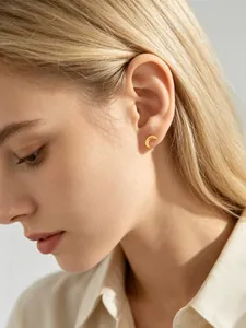 Gedetailleerde opname van een minimalistisch gouden maan oorknopje op een model