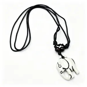Detail van een witte olifant hanger van hars met botlook en zwart koord met houten kralen